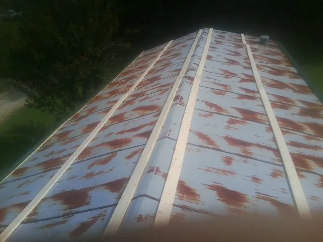 Rusted metal roof panels with new wood purlins before replacement — Storm Damage Roof Repair in Saint Paris by Roofing Brothers