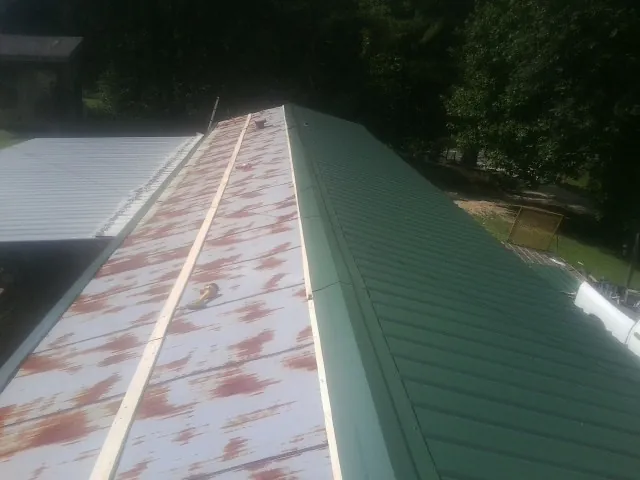 Old rusted panels beside newly installed green metal roofing — Wind Damage Roof Repair by Roofing Brothers in Saint Paris