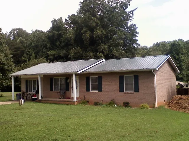 Gray metal roof on a brick ranch house with a side carport in Saint Paris