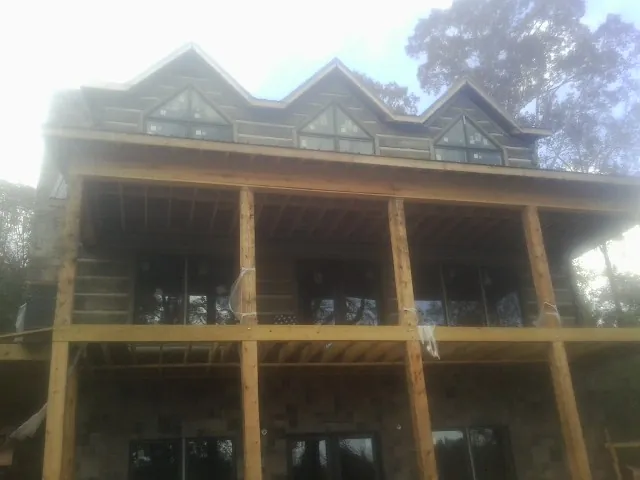 Dormers and porch framing on a large log home under construction — Roof Coating work by our crew in Saint Paris