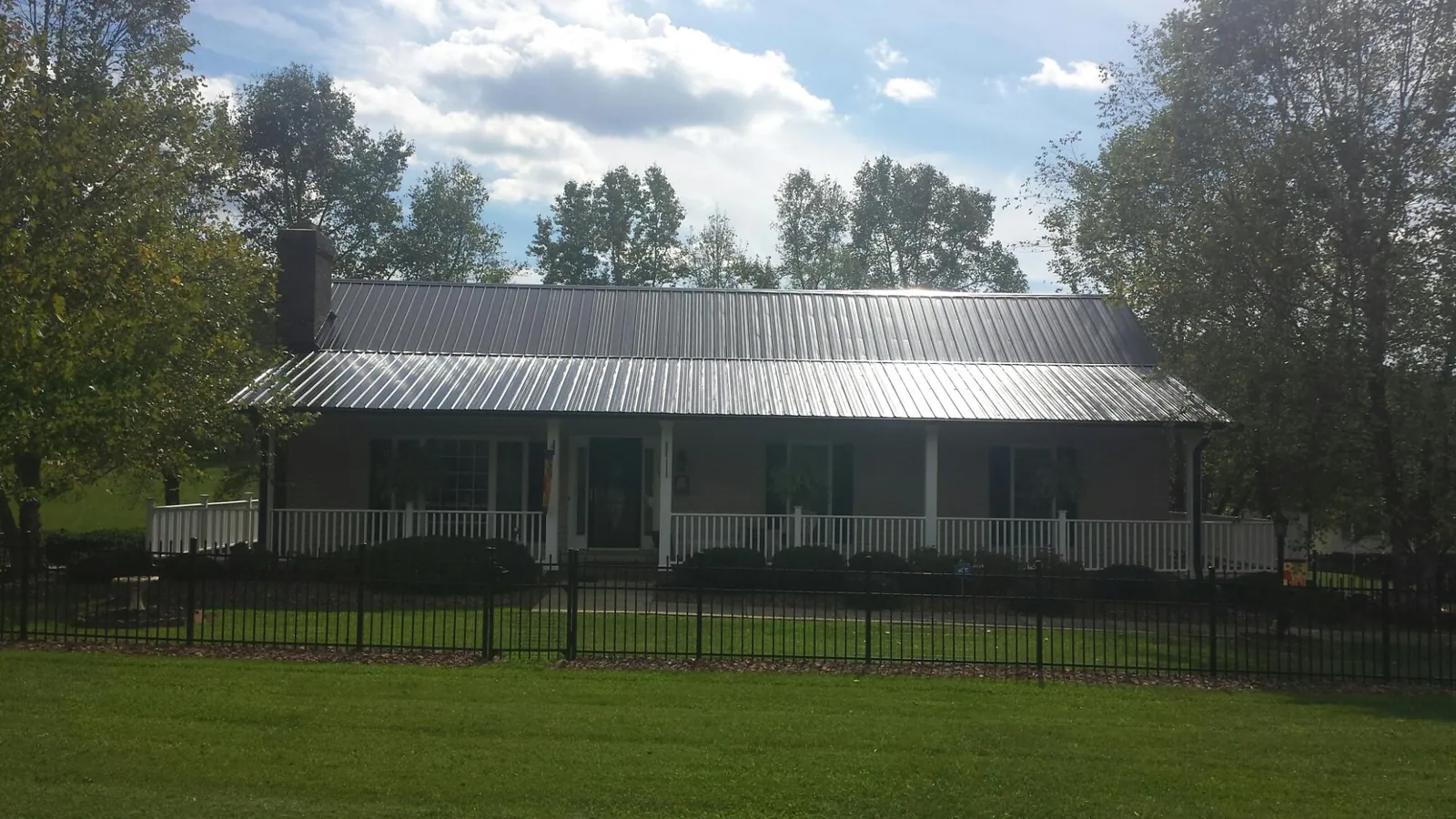 Gray metal roof on a brick ranch with a full width front porch — Gutter Guard Installation work by our crew in Saint Paris