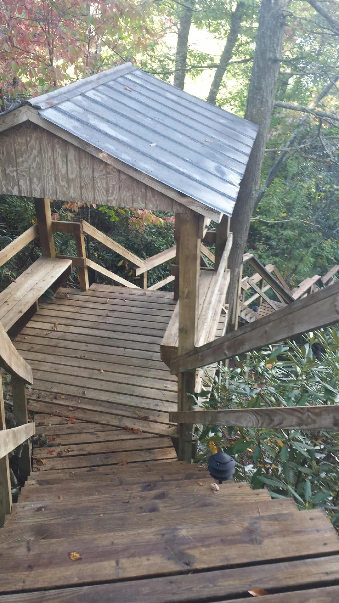 Metal roofed shelter over wooden steps on a wooded walkway — Skylight Repair & Installation work by our crew in Saint Paris