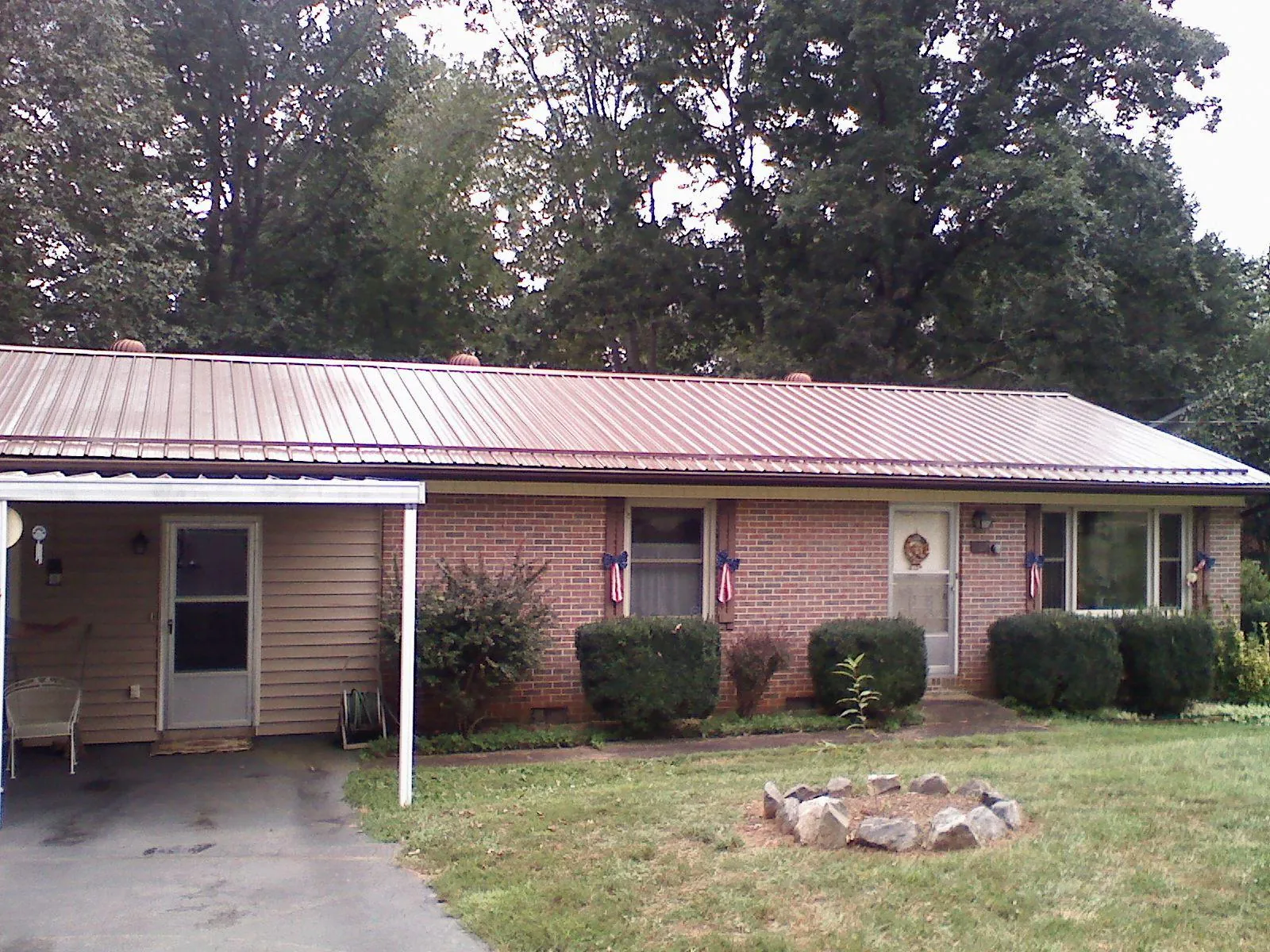 Bronze metal roof and carport on a brick ranch home — Roof Repair work by our crew in Saint Paris