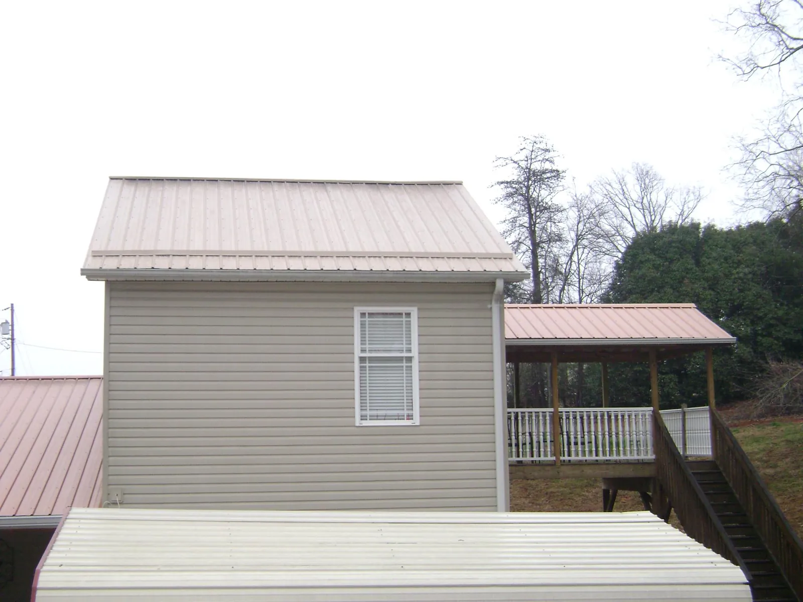 Tan metal roofs on a two story addition and attached porch, from a Roof Replacement job in Saint Paris