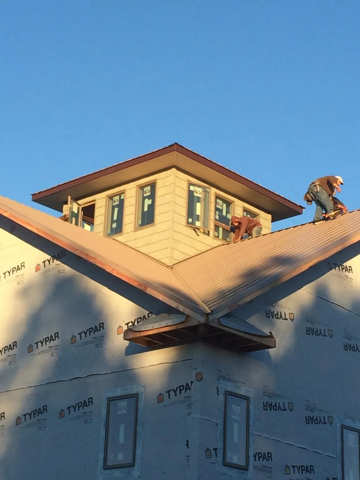 Roofers working around a rooftop cupola on a new metal roof at sunset — Roof Waterproofing in Saint Paris by Roofing Brothers